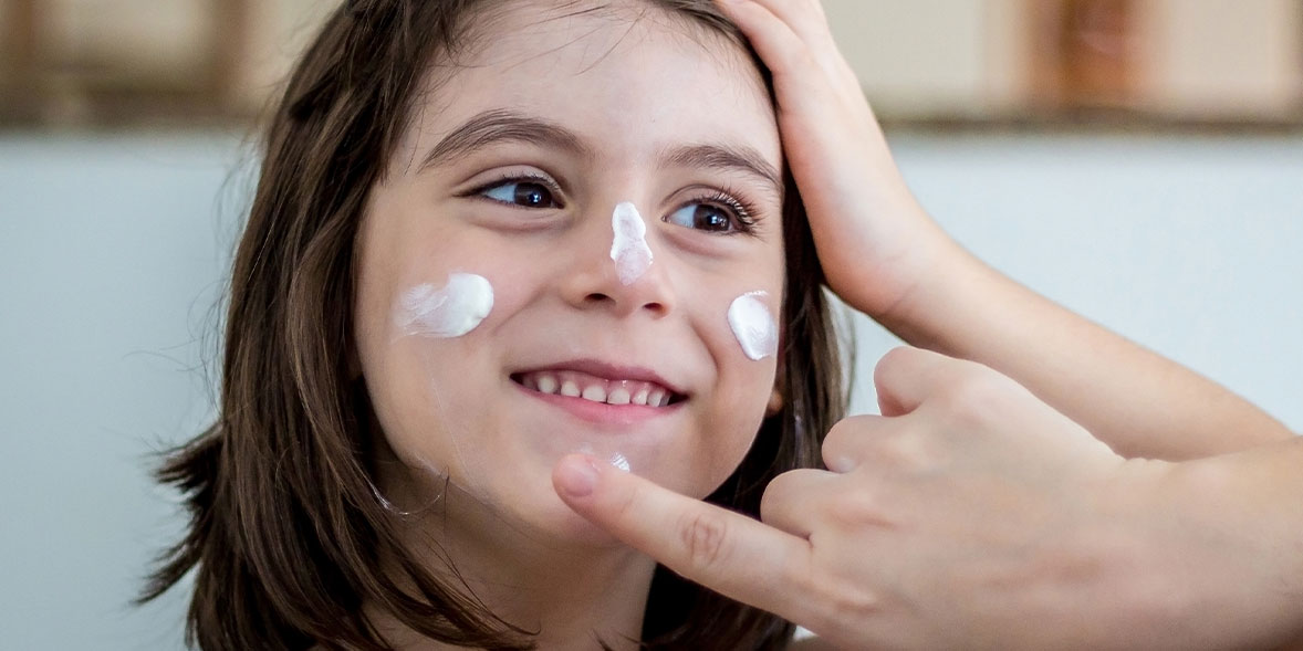 Child having sunscreen dabbed onto their face