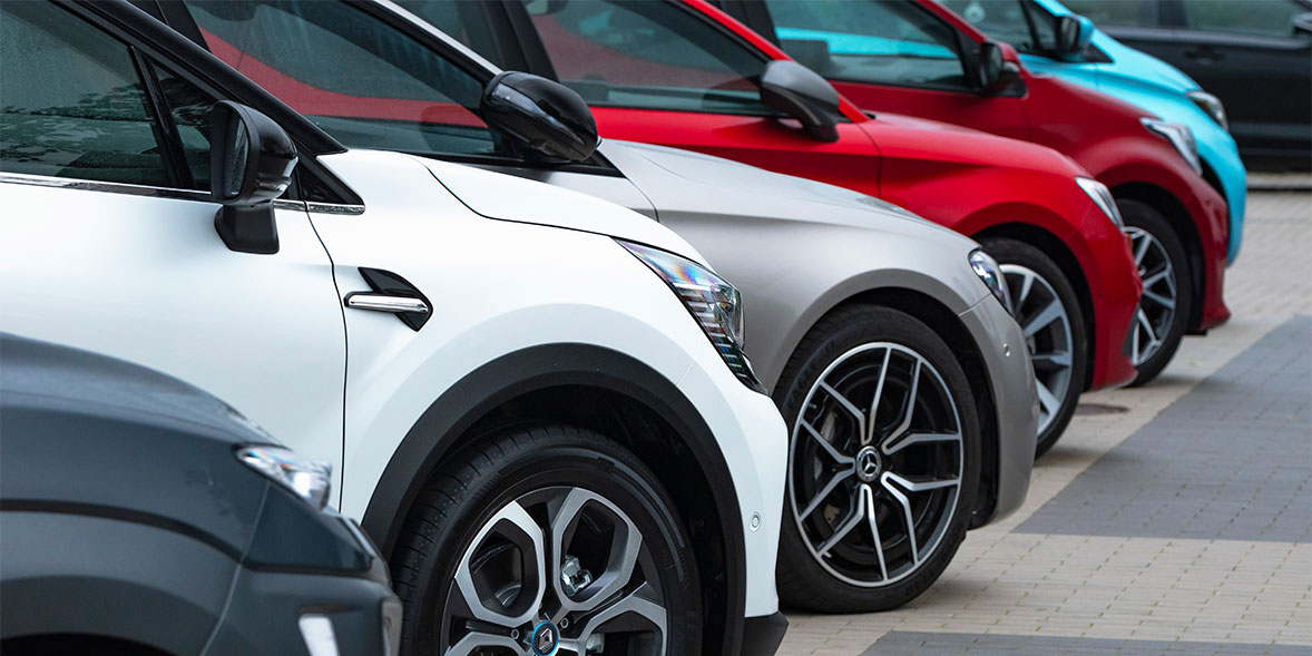 Row of parked cars showcasing various colors, including white, silver, and red, with a focus on their wheels and design.