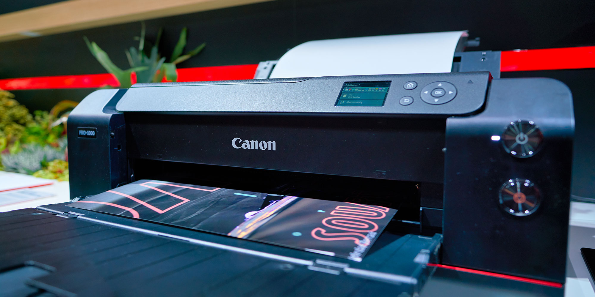 A black Canon printer with a printed document showing colorful graphs emerging from its paper tray.