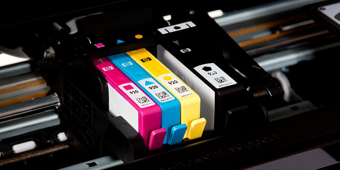 Three ink cartridges in cyan, magenta, and yellow, installed in a printer, with labels and QR codes visible.