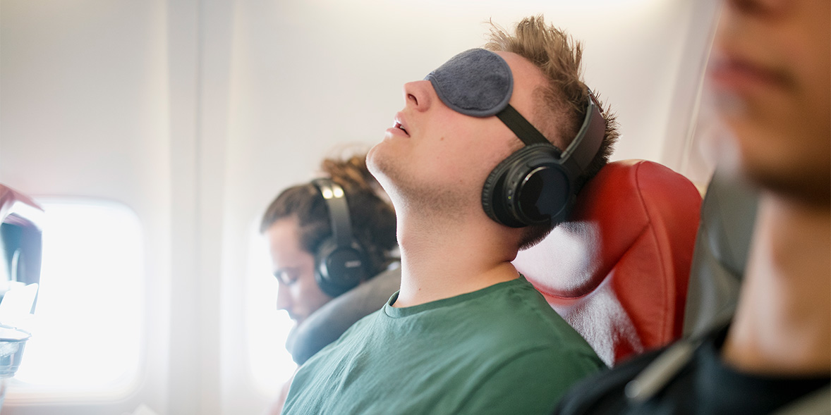 A sleeping passenger on a flight wearing an eye mask
