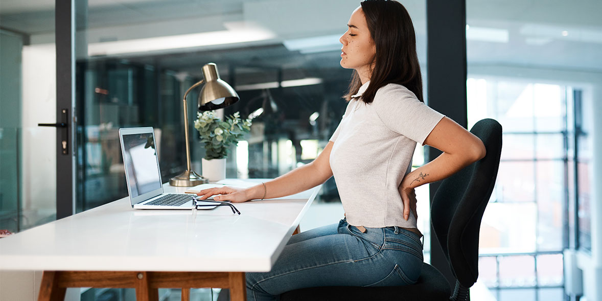 Person suffering from back pain at desk