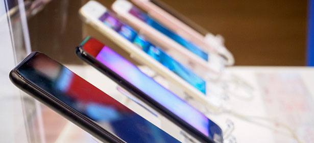 Several smartphones with colorful screens displayed on stands, showcasing a variety of designs and colors.